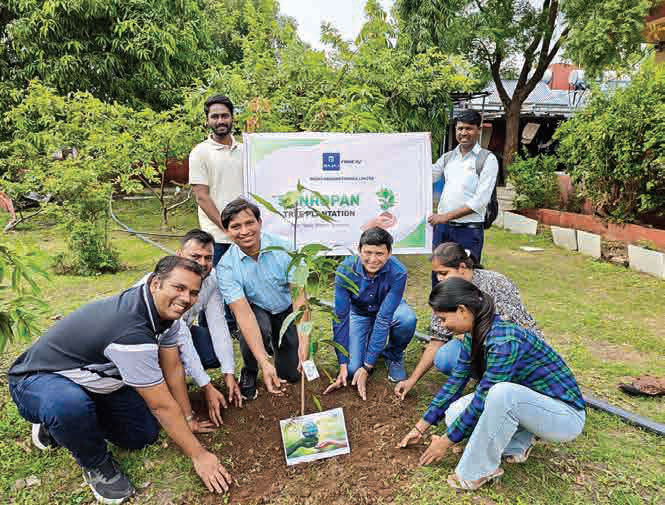 Bajaj Finserv employees kneeling to plant saplings during a tree-plantation drive.