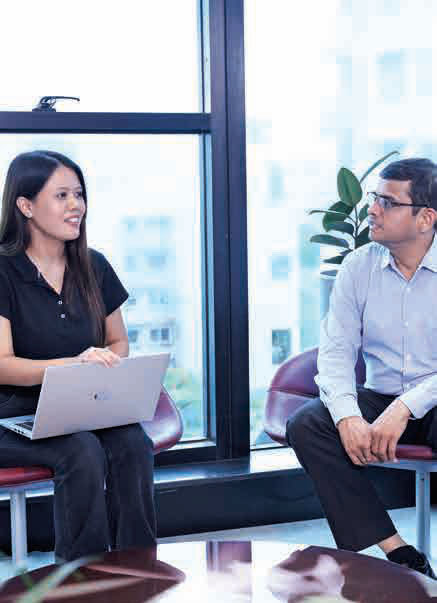 Two Bajaj Finserv colleagues talking beside a large office window.