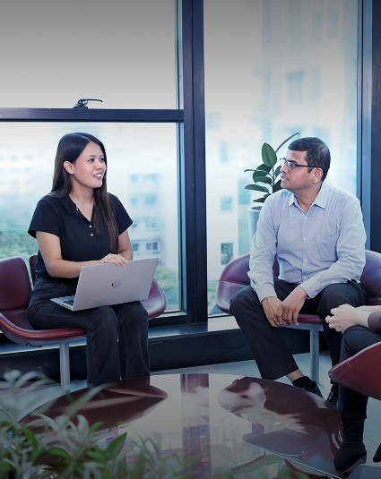 Two Bajaj Finserv colleagues talking beside a large office window